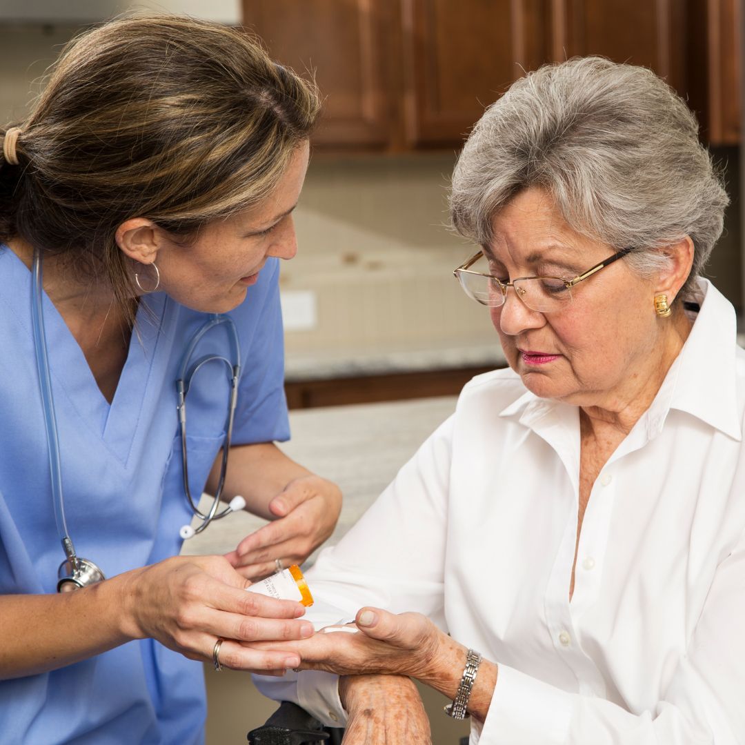 A female nurse helping a woman with her medication.