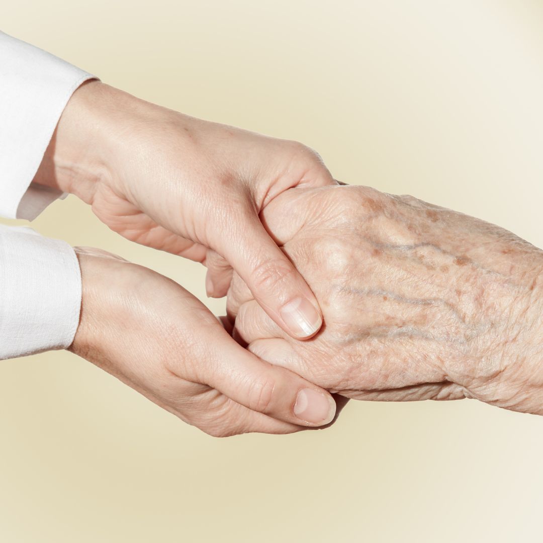 A young person holding hands with an elderly person.