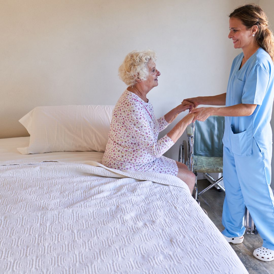 Elderly woman being helped out of bed with a nurse